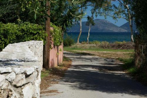 a road with a stone wall next to the ocean at Sami Beach Villas Thalia in Sami