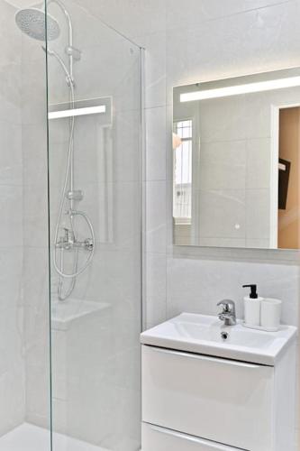 une salle de bain blanche avec un lavabo et une douche dans l'établissement Petit studio plein pied aux portes de Paris, à Le Pré-Saint-Gervais