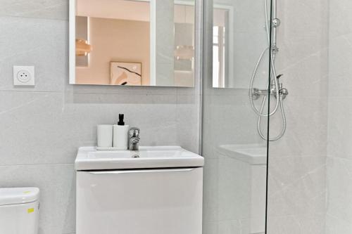 une salle de bain blanche avec un lavabo et une douche dans l'établissement Studio équipé et confortable Porte de Pantin, à Le Pré-Saint-Gervais