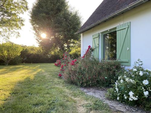 une maison blanche avec une porte verte et quelques fleurs dans l'établissement La Corti, à Tillières-sur-Avre