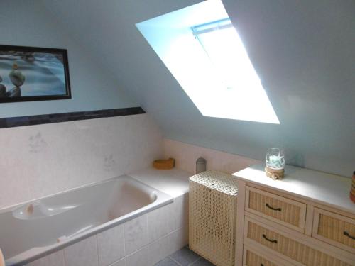 La salle de bains est pourvue d'une grande baignoire et d'une lucarne. dans l'établissement Maison 4 pièces 6 personnes proche de la mer - WIFI - SOAZIG, à Saint-Gildas-de-Rhuys