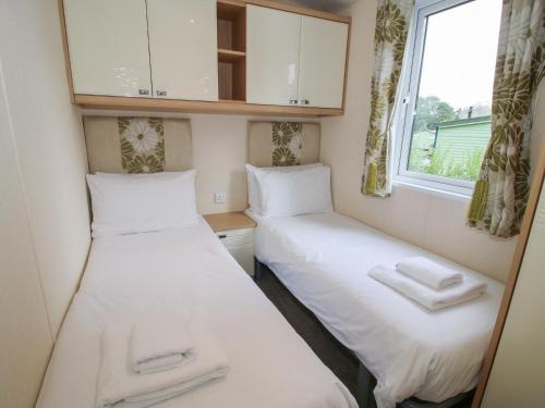 two beds in a small room with a window at Dove in Leominster