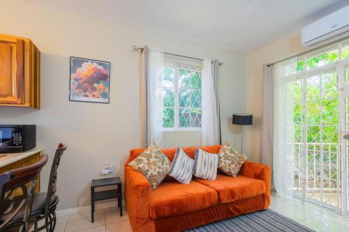 an orange couch in a living room with windows at Musgrave AnneX- comfy 1 bedroom apartments in Kingston