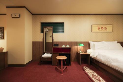 1 dormitorio con cama, mesa y taburete en Stay Passport Hongkong Goseong, en Goseong