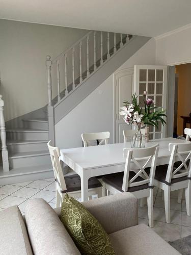 une salle à manger blanche avec une table et des chaises blanches dans l'établissement Duplex cosy très proche de La Défense, à Nanterre
