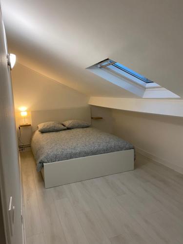 - une petite chambre avec un lit et une lucarne dans l'établissement Duplex cosy très proche de La Défense, à Nanterre