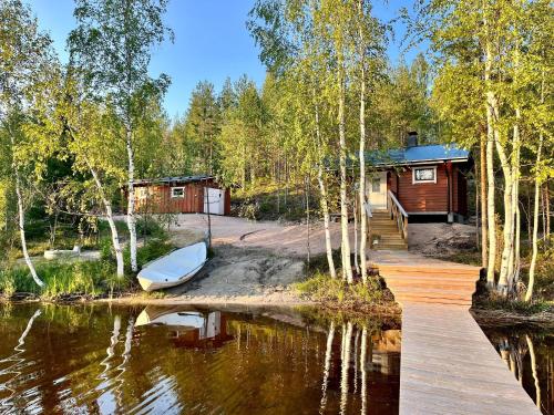 a cabin with a dock and a boat in the water at Saunamökki Iltahurri, LaatuLomat in Telakanava