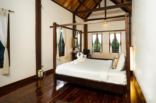 a bedroom with a canopy bed in a room at Villa Khoum Xieng Thong Boutique in Luang Prabang