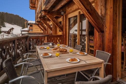 - une table en bois sur une terrasse avec de la nourriture dans l'établissement Chalet Petit Mouflon, aux Gets