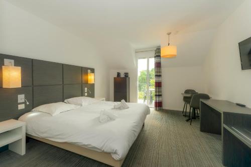 a bedroom with a large white bed and a desk at Résidence Goélia Le Domaine de Pont-Aven in Pont-Aven