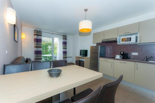 - une cuisine avec une table, des chaises et un comptoir dans l'établissement Résidence Goélia Le Domaine de Pont-Aven, à Pont-Aven