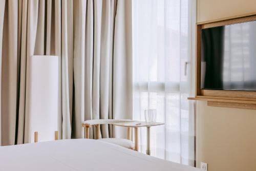 a bedroom with a bed and a tv and a chair at Sangha Toulouse in Toulouse