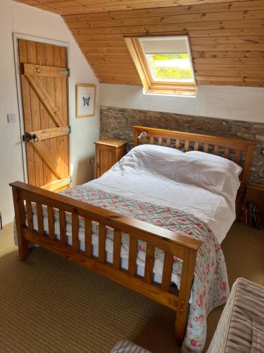 a bedroom with a wooden bed with a wooden door at Canfee Cottage in Bunaw
