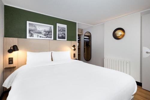 a bedroom with a white bed and a green wall at Campanile NATURE - Bordeaux Sud Pessac in Pessac
