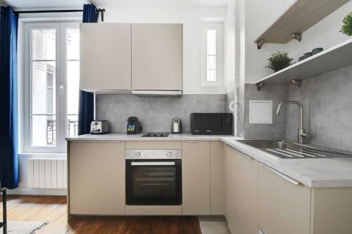 une cuisine avec des armoires blanches, un évier et une cuisinière dans l'établissement Charming apartment -1BR-4P- Gare Montparnasse, à Paris