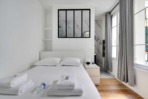 une chambre blanche avec un lit avec des serviettes dessus dans l'établissement Charming apartment -1BR-4P- Gare Montparnasse, à Paris