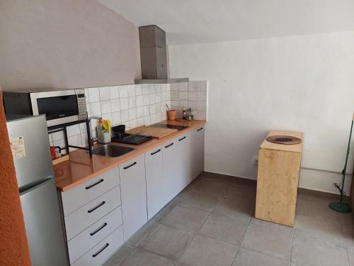 a kitchen with white cabinets and a sink and a refrigerator at Estudi ideal en una masia in Amer
