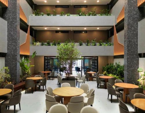 a restaurant with tables and chairs and plants at Beach Haus beira mar bessa in Tambaú