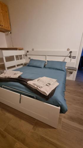 a white bed with blue pillows on top of it at Maso kreuzberg appartamento in mansarda vista montagne in Trento