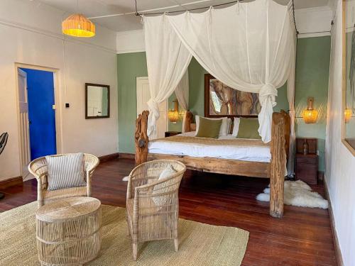 una camera con letto a baldacchino e 2 sedie di Sanctuary Farm House 5-bedroom Lodge In Wildlife a Naivasha