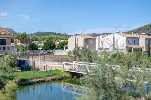 a bridge over a river in a town with houses at Que Bo in Alcudia