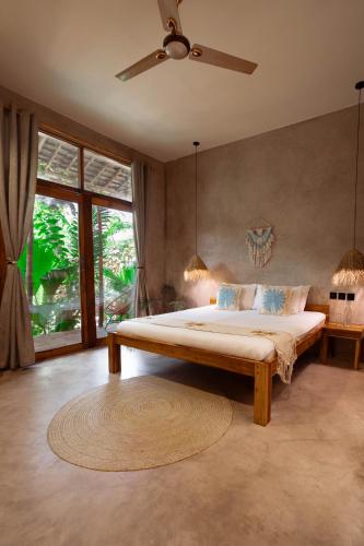 a bedroom with a large bed with a ceiling fan at The Garten Living in Paje