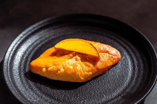 a piece of food with an orange slice on a black plate at The Garten Living in Paje