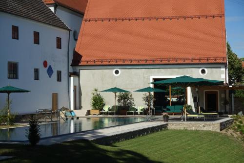 a house with a swimming pool with green umbrellas at Romantik Hotel Zum Klosterbräu in Neuburg an der Donau