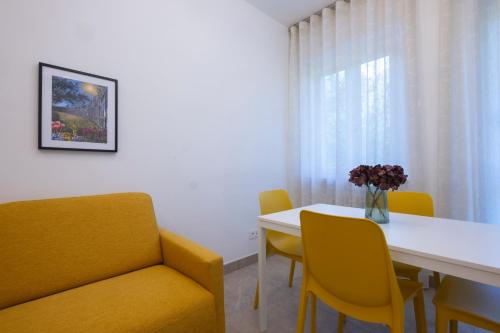 a room with a table and chairs and a yellow couch at MyVilla - Ivrea via Rosselli 9 in Ivrea