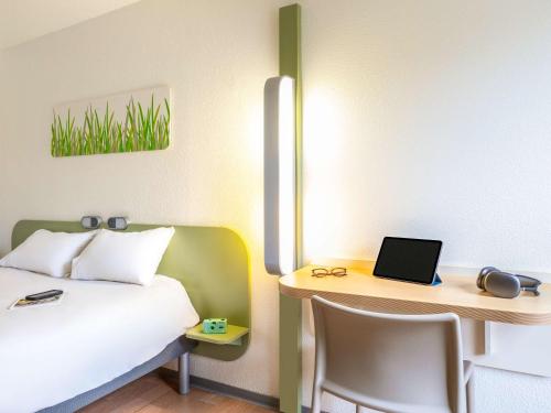 a bedroom with a bed and a desk with a laptop at ibis budget Compiègne Centre-Ville in Compiègne