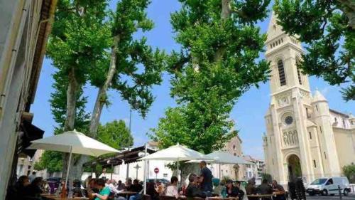 un groupe de personnes assises à des tables devant une église dans l'établissement Manu's appartment, à Marseille