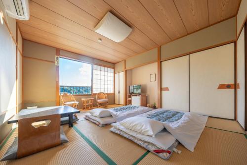 a bedroom with a bed and a desk and a window at くつろぎと料理の御宿花さと -Hanasato- in Minamiizu