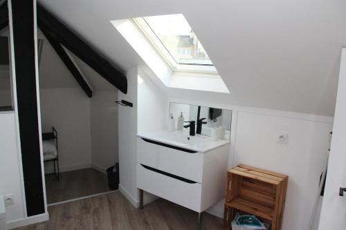 een badkamer met een wastafel en een dakraam bij L'appart T2 de la gare - Cambrai in Cambrai