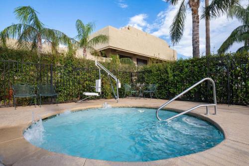 a small swimming pool in a yard with palm trees at Ramada by Wyndham Tucson in Tucson