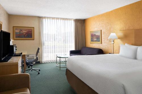 a hotel room with a bed and a desk and a television at Ramada by Wyndham Tucson in Tucson