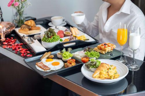 a woman is holding a tray of breakfast foods at Park Plaza Bangkok Soi 18 in Bangkok