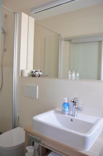 a white bathroom with a sink and a mirror at Hotel Restaurant "Zur Post" in Holdorf