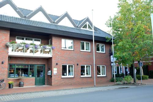 a red brick building with windows and flowers on the balconies at Hotel Restaurant "Zur Post" in Holdorf