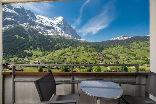 a table and chairs on a balcony with mountains at Jungfrau Lodge, Annex Crystal in Grindelwald