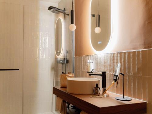 a bathroom with a sink and a mirror and a shower at Hôtel Fort St Laurent Lyon - Handwritten Collection in Lyon