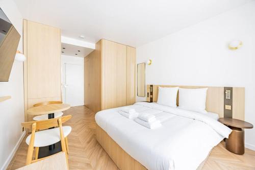- une chambre avec un grand lit blanc et des placards en bois dans l'établissement 154 Suite luxueuse-Etienne Marcel-Châtelet-Paris 3, à Paris