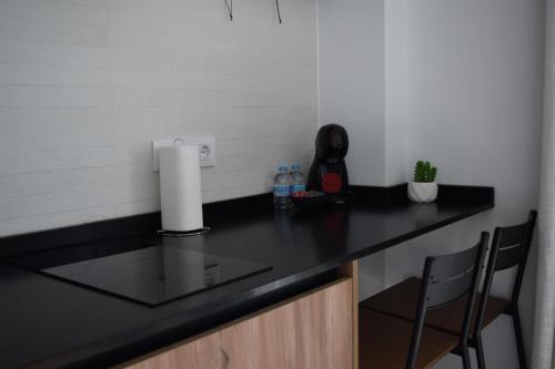 a kitchen with a black counter top and two chairs at Quercus in Pozoblanco