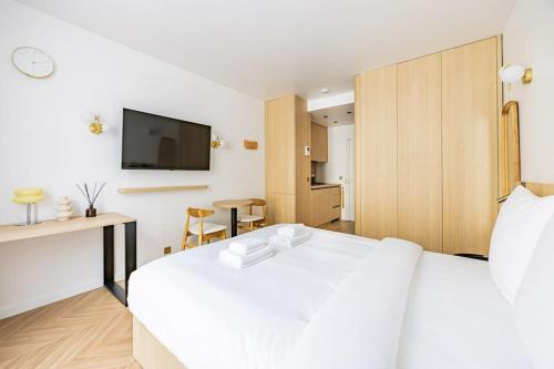 Cette chambre comprend un lit blanc et une télévision murale. dans l'établissement 153 Suite luxueuse-Etienne Marcel-Châtelet-Paris 3, à Paris