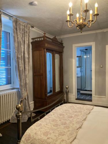 a bedroom with a bed and a chandelier and windows at La Ruche, Chaillac in Chaillac