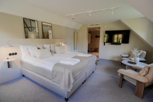 a large white bedroom with a large bed and a chair at Margretetorps Gästgifvaregård in Hjärnarp