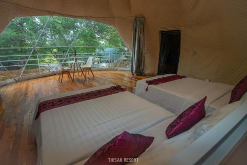 two beds in a room with a balcony at Thisak Resort Cheung phnom kulen in Siem Reap