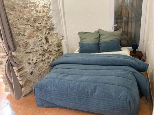 - une chambre dotée d'un lit avec des draps bleus et un mur en pierre dans l'établissement Nid Douillet à Hyères, à Hyères