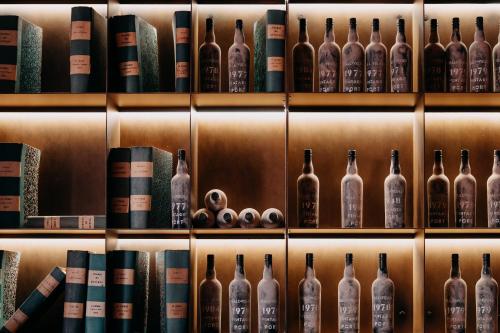 a shelf with bottles of wine and books at Casa da Companhia, Vignette Collection by IHG in Porto