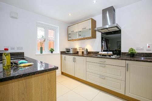 a kitchen with white cabinets and a black counter top at Detached 4 Bed-UltraFast Wifi Garden Free Parking in Milton Keynes