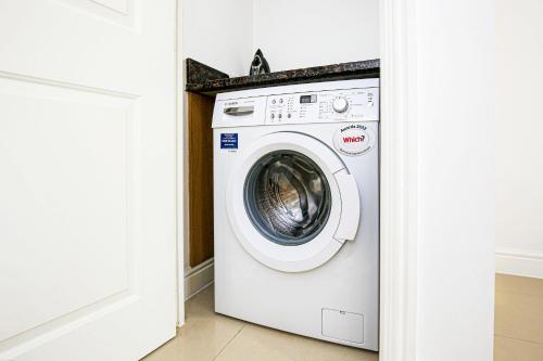a white washing machine in a white laundry room at Detached 4 Bed-UltraFast Wifi Garden Free Parking in Milton Keynes